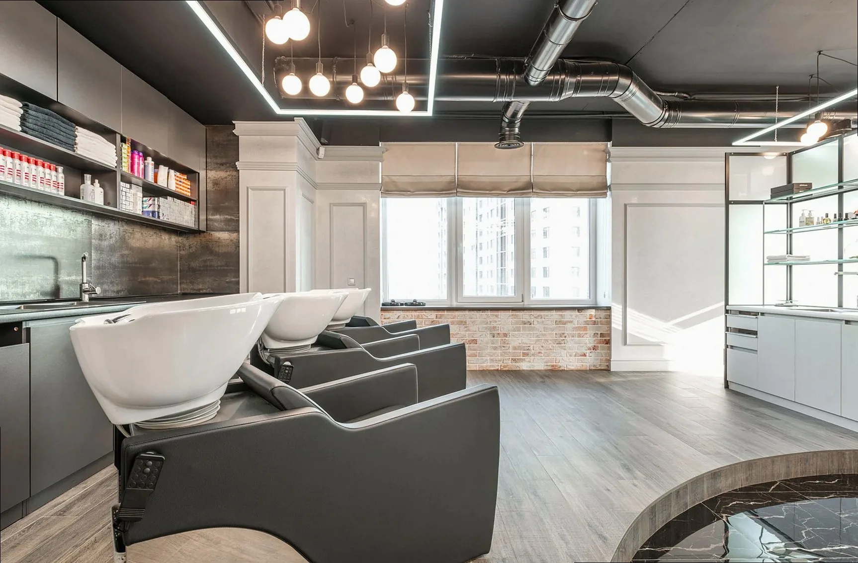 Black backwash chairs with sinks placed in modern spacious beauty salon with window and arrangement of cosmetology suppl