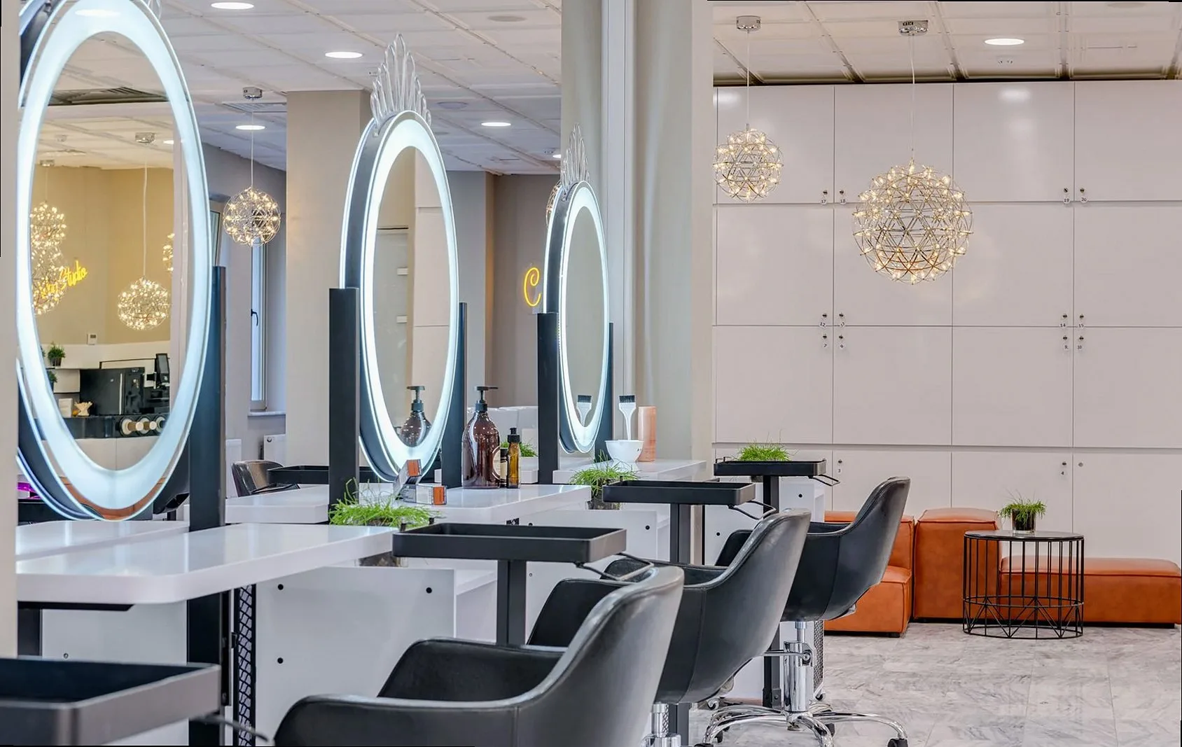 Bright and elegant hair salon interior featuring modern lighting and round mirrors for a chic and relaxing atmosphere.